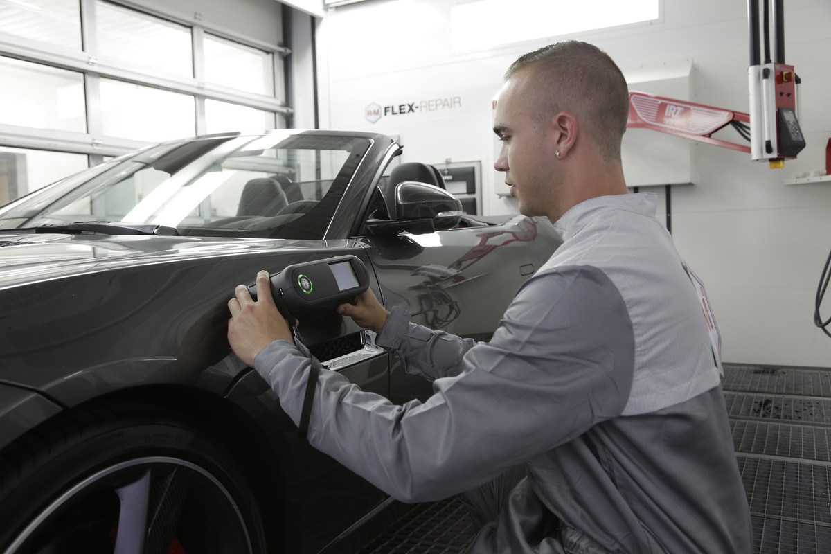 Technician using professional colour-matching equipment on a vehicle panel