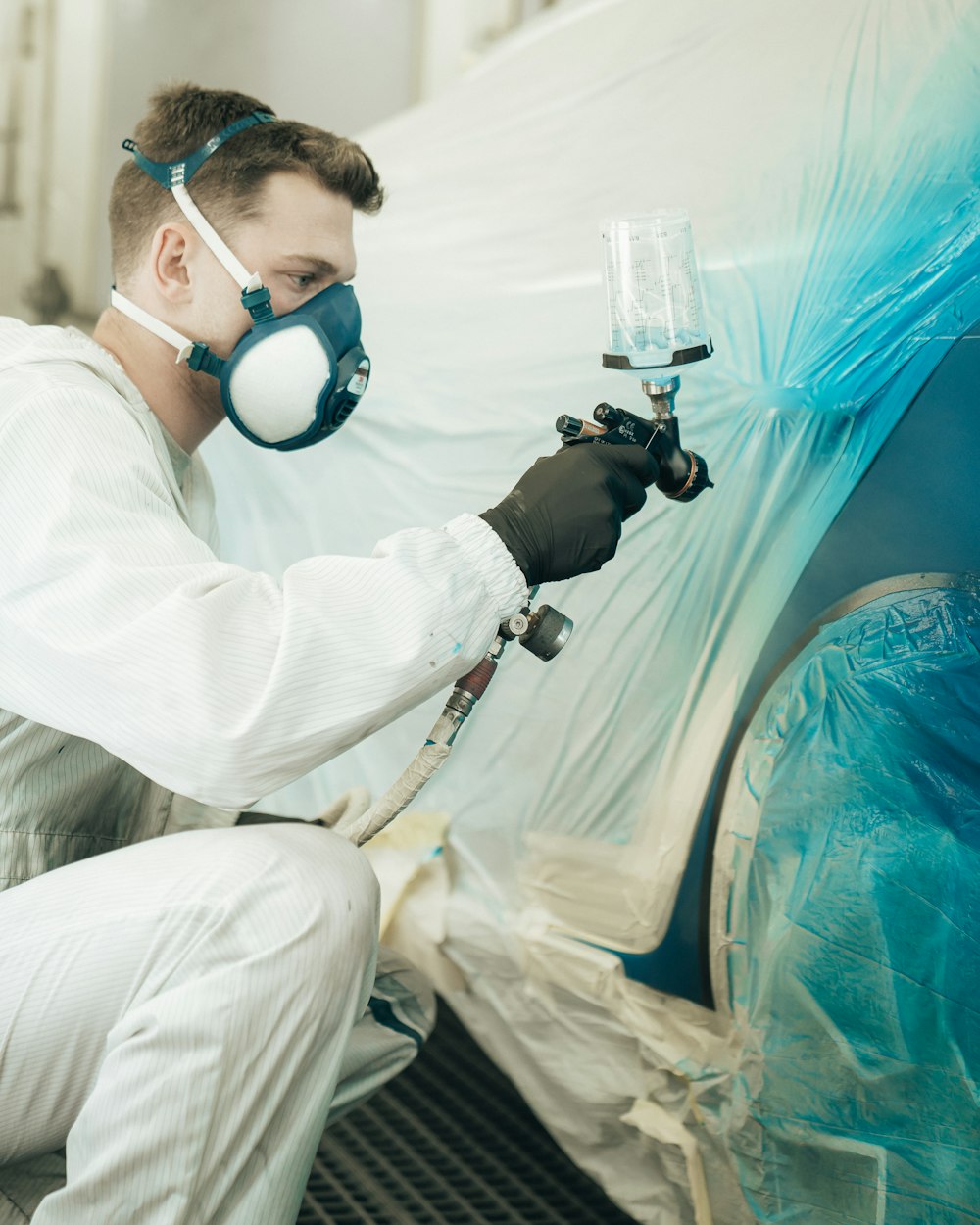 A refinishing technician applying automotive paint